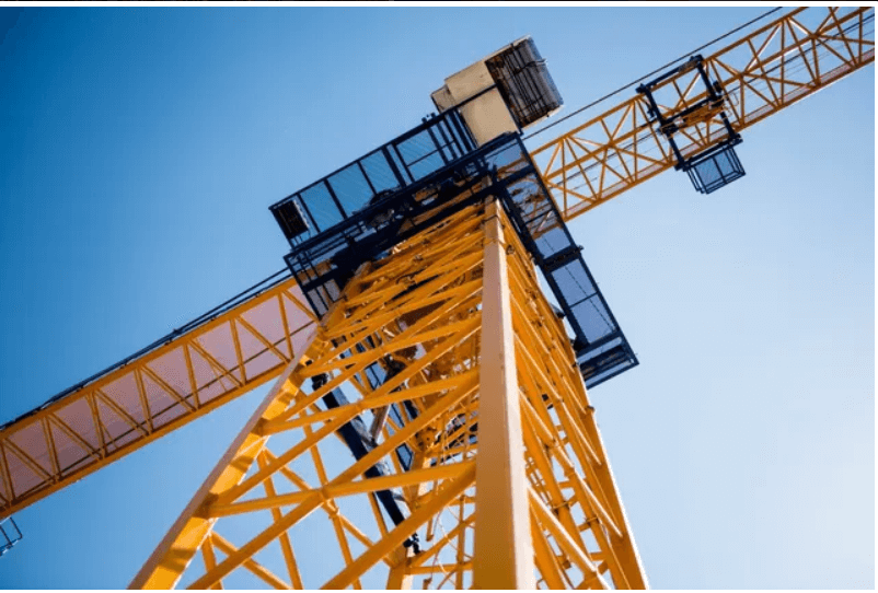 Yellow construction crane against clear blue sky.