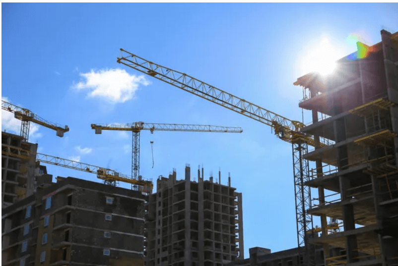 Construction site with cranes under blue sky.