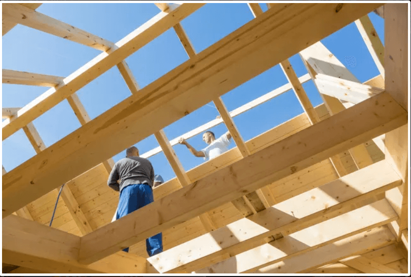 Construction workers building wooden roof frame.