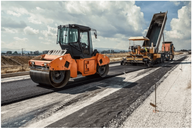 Road construction with machinery on asphalt surface.